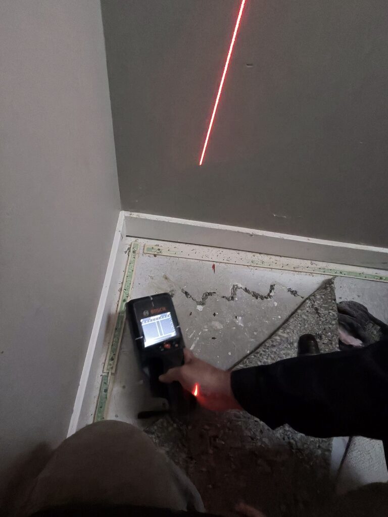 Bye Radon technician using laser level to locate wall penetration point before radon pipe installation in Calgary home