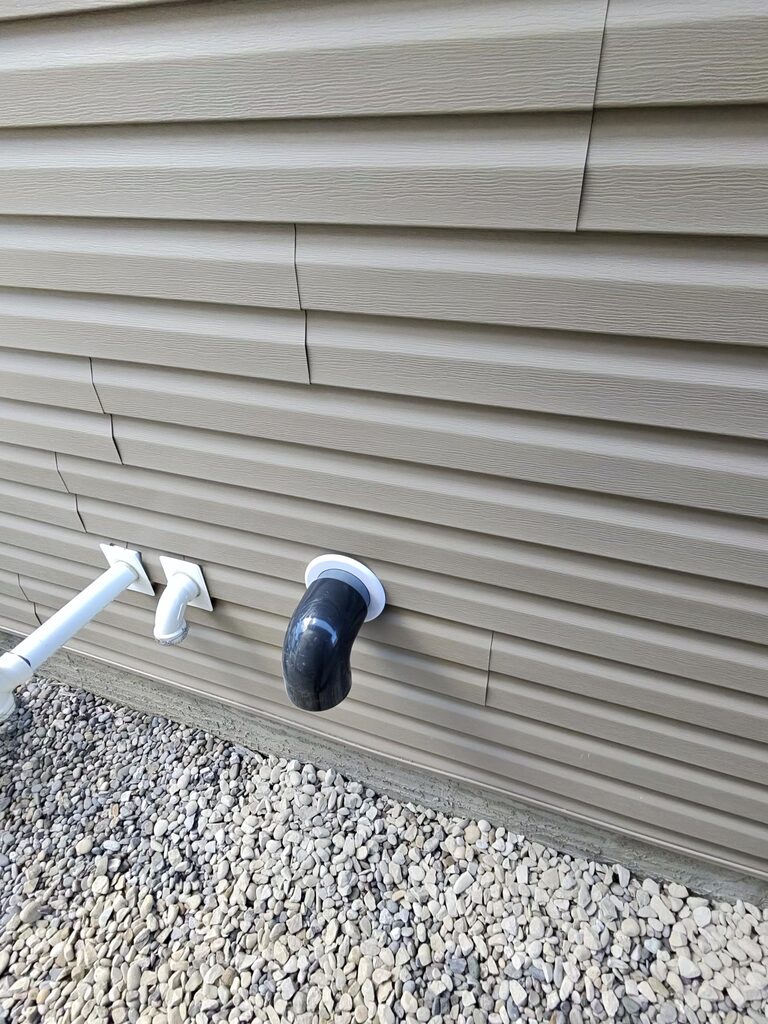Radon mitigation exhaust pipe exit cleanly installed through Airdrie home exterior siding with protective cap